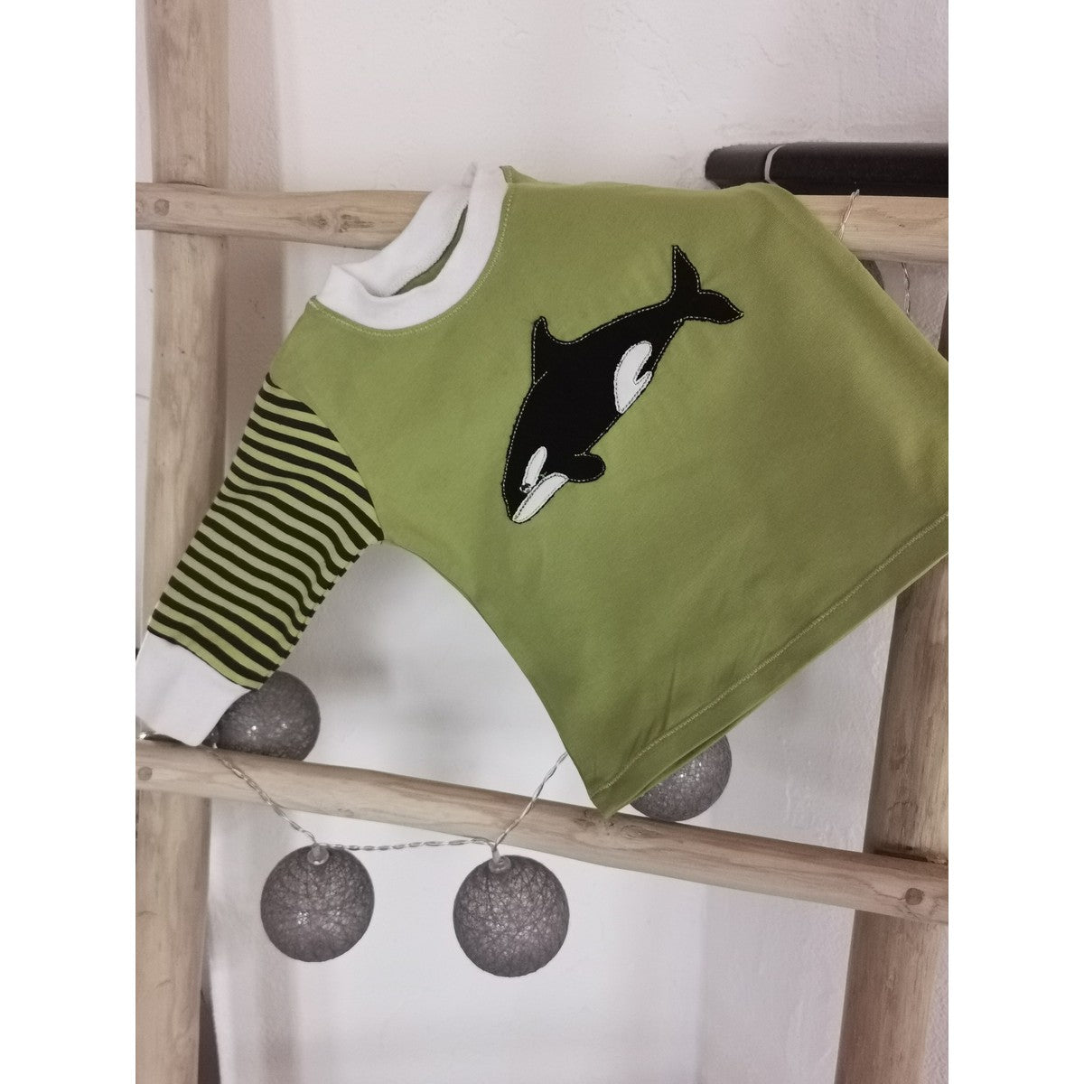Stickdatei Walfamilie – grüner Kinderpullover mit gestreiftem Ärmel und schwarz-weißem Orca als Applikation