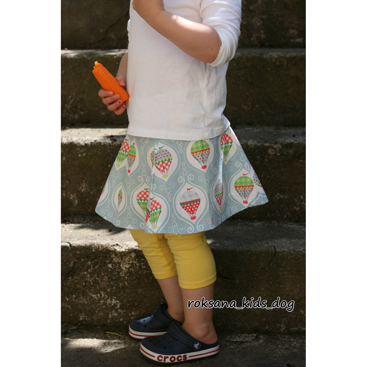 Trapezrock Sandra Schnittmuster – Rock mit Erdbeer-Print und gelber Leggings auf einer Treppe (genähtes Designbeispiel)