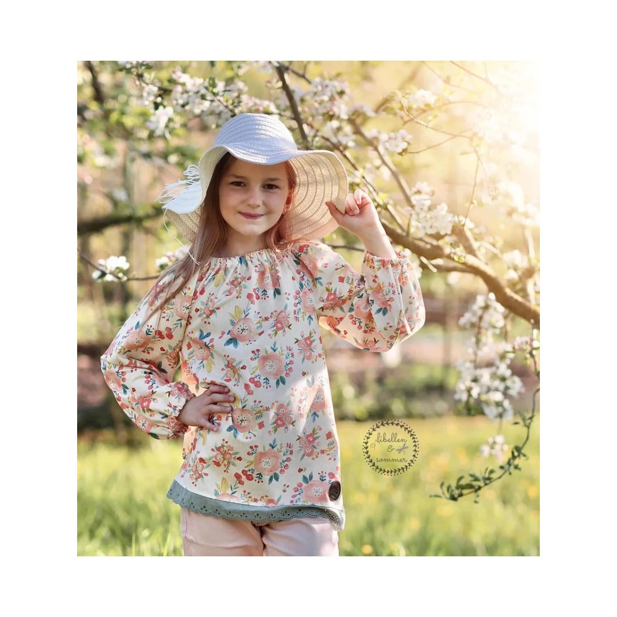 Tunika Kleid Talia Schnittmuster – Mädchen in geblümter Tunika unter Blüten (genähtes Designbeispiel)