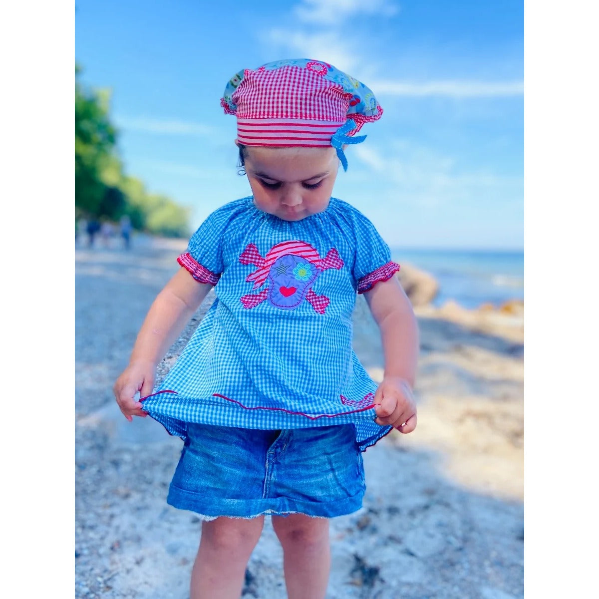 Tunika Kleid Talia Schnittmuster – Kind mit Mütze in blauer Tunika am Strand (genähtes Designbeispiel)